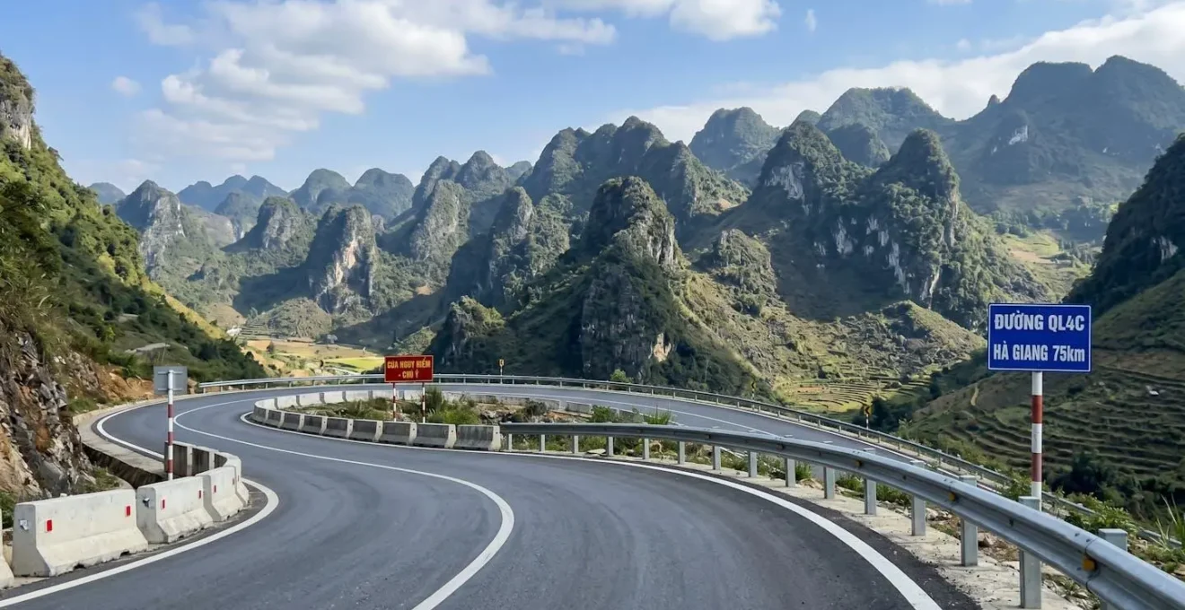 Route asphaltée serpentant à travers les pics karstiques calcaires du géoparc de Ha Giang sous une lumière naturelle éclatante